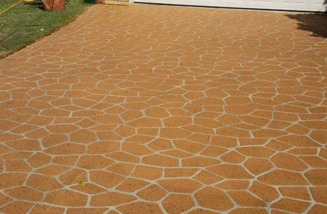 Terracotta stencilled concrete driveway leading to a double garage
