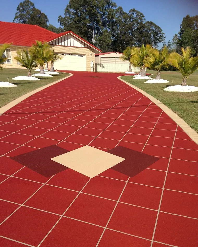 Deep red coloured concrete driveway with a cream and burgundy diamond feature inlay