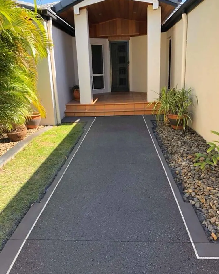Charcoal exposed aggregate path leading to a timber-lined front entry