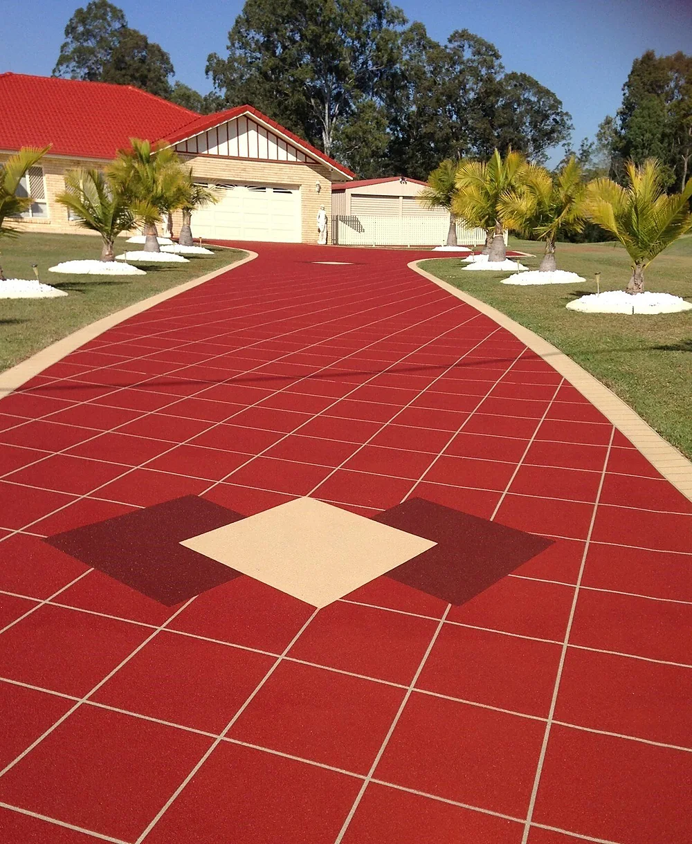 Coloured and stencilled concrete driveway curving to a double garage, bordered by palms