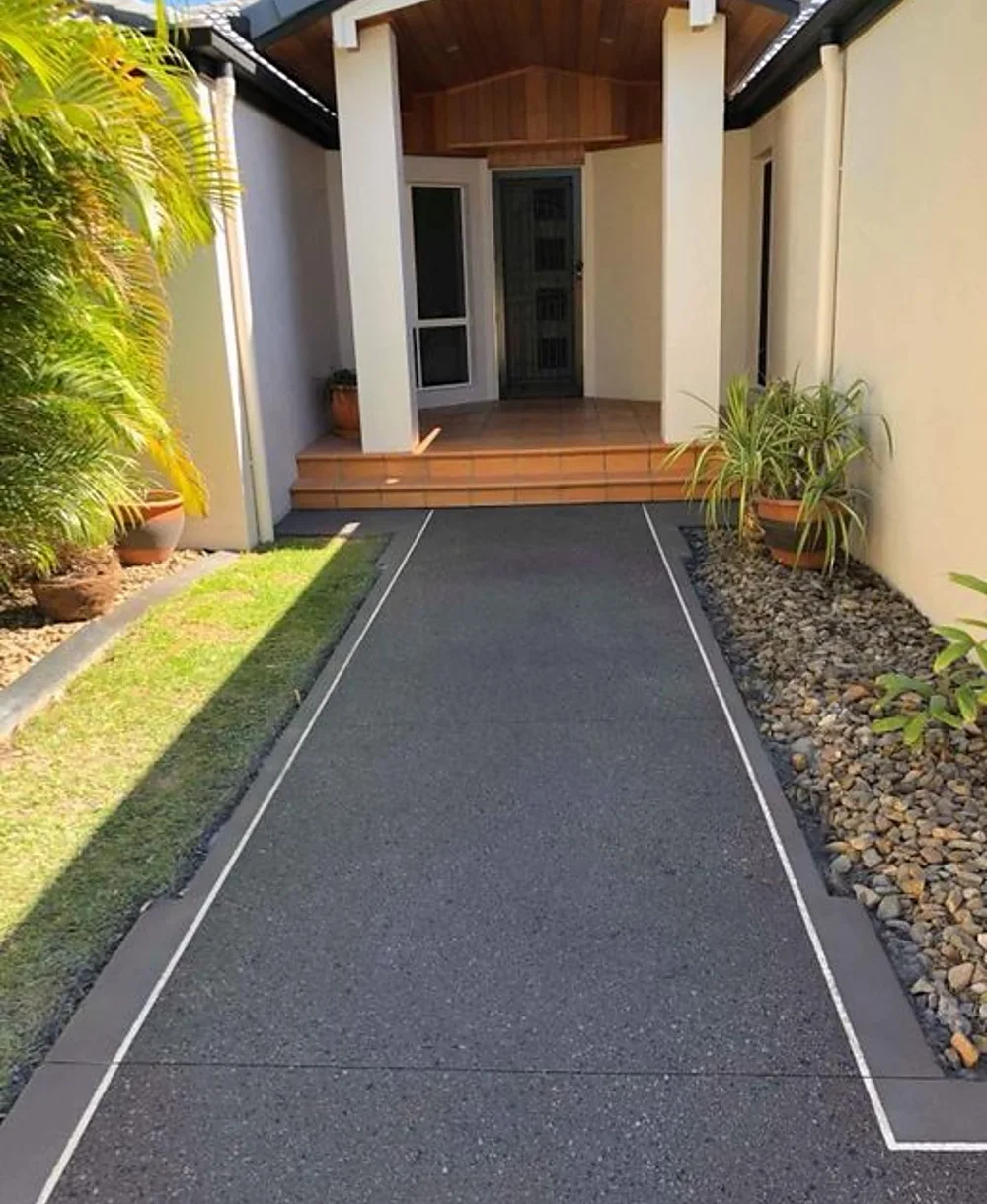 Charcoal exposed aggregate path leading to a timber-lined front entry