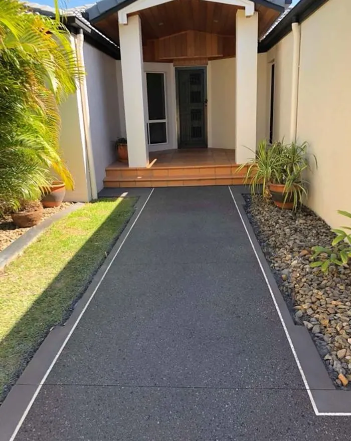 Charcoal exposed aggregate path leading to a timber-lined entry