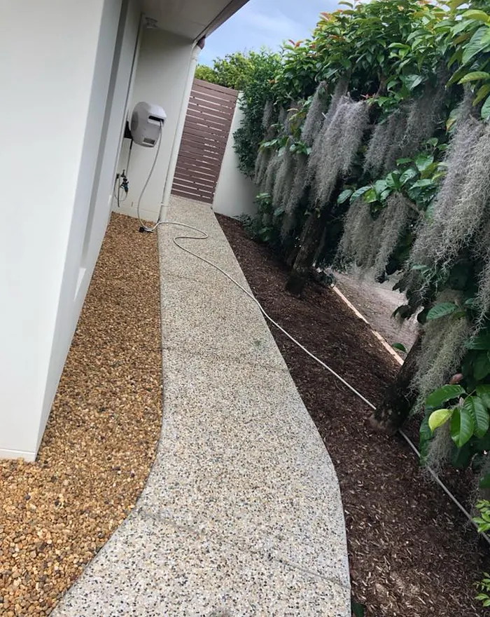 Light exposed aggregate path beside a garden bed